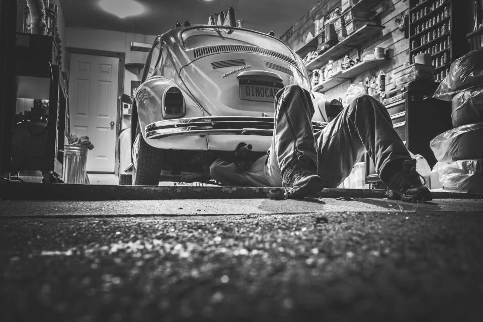 Mecánico trabajando bajo un coche en un taller — ejemplo de estudio para un taller ficticio